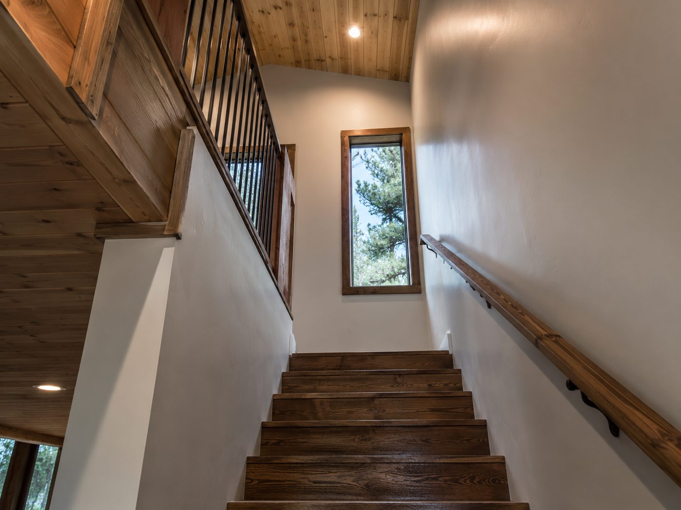 Tall interior stairwell with painted walls and a stained handrail in Big Bear